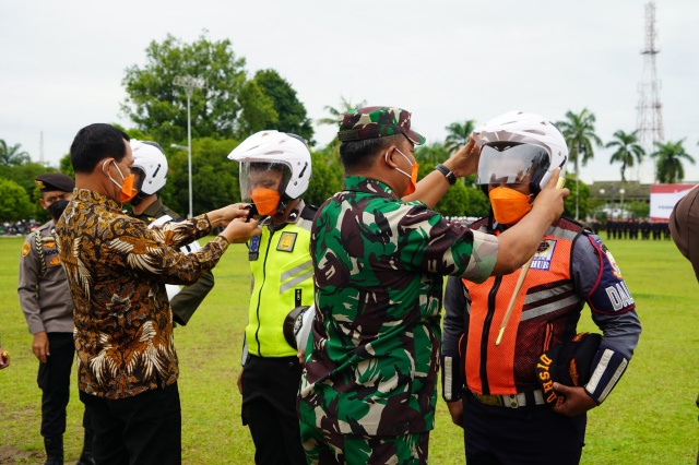 Danrem 042/Gapu Brigjen TNI Supriono, S.IP., M.M., secara simbolis memakaikan helm kepada perwakilan peserta Apel Nyata Peningkatan Tertib Berlalu Lintas Provinsi Jambi (Foto. Penrem 042/Gapu)